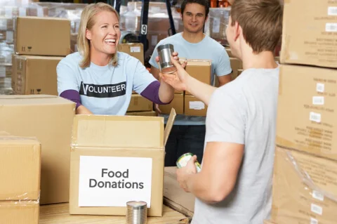 A volunteer giving a man a can goods