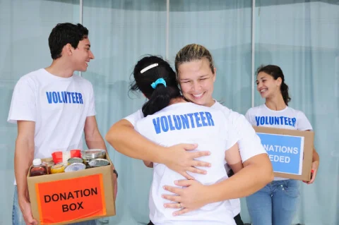 Two volunteer hugging each other